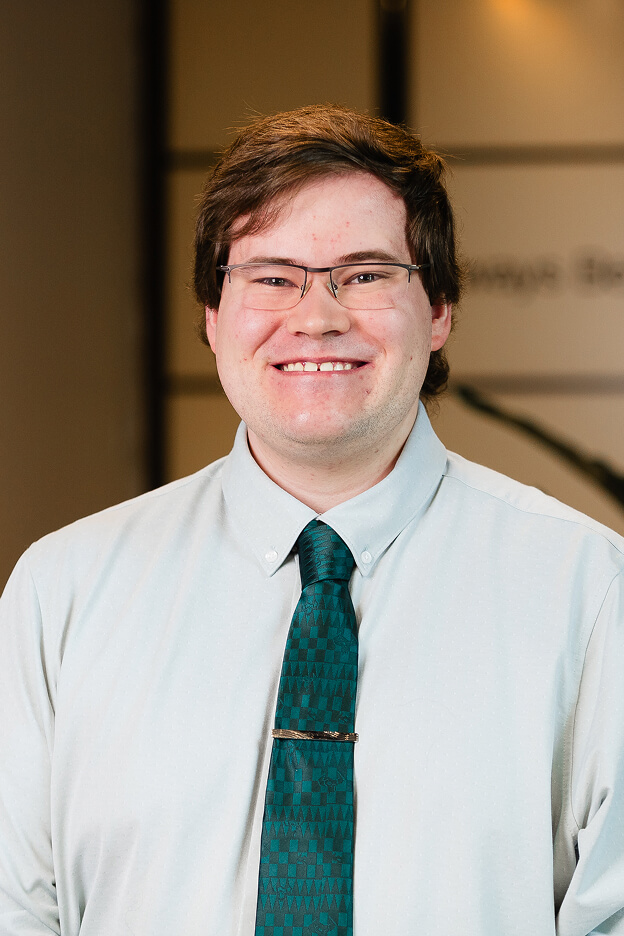 Professional portrait of a man in a light blue shirt and patterned teal tie at Always Beyond, Calgary IT services company.