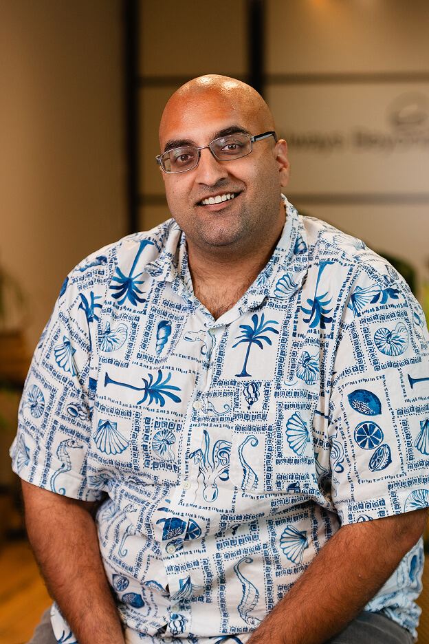 Team member Jag wearing a blue and white patterned shirt seated inside Always Beyond Calgary IT services office.