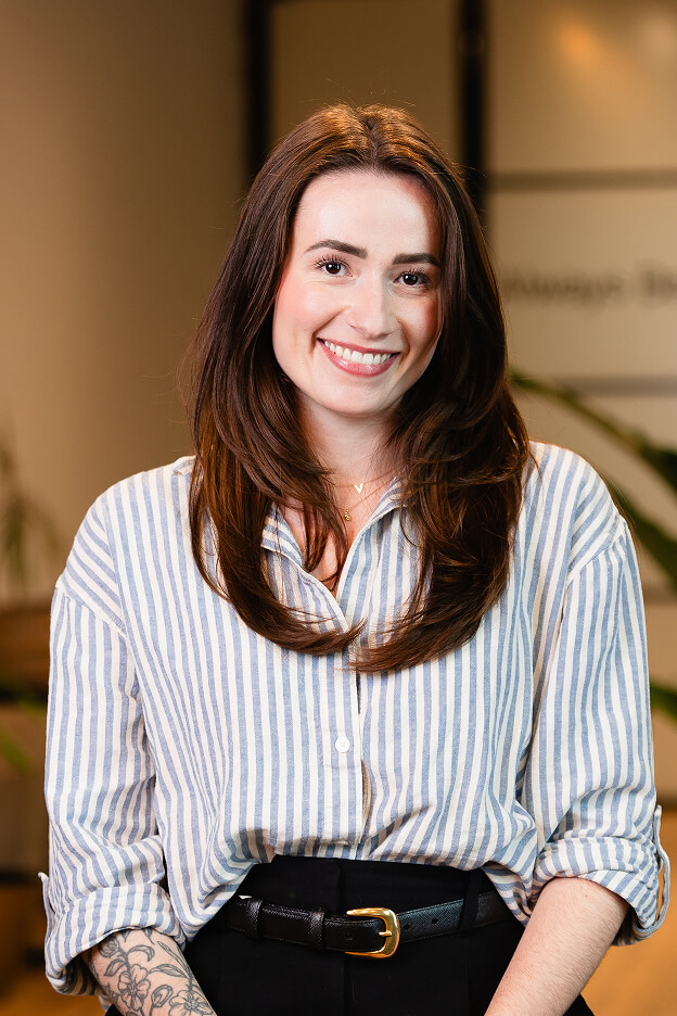 Team member at Always Beyond Calgary IT services wearing striped shirt and black pants with tattooed arm visible.