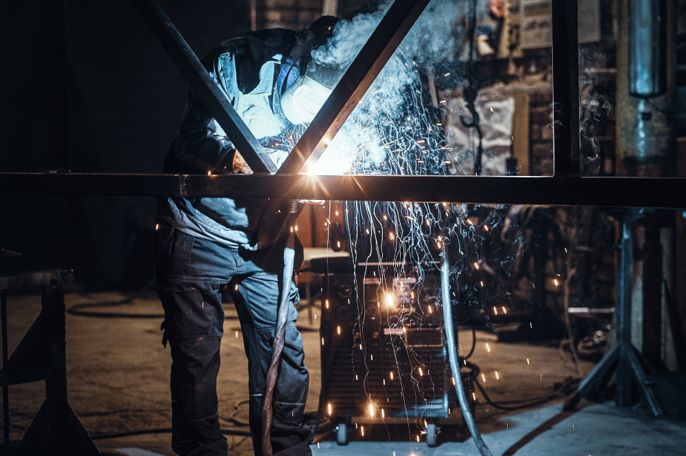 Schweißarbeiten und Metallbau in belebter Metallfabrik.