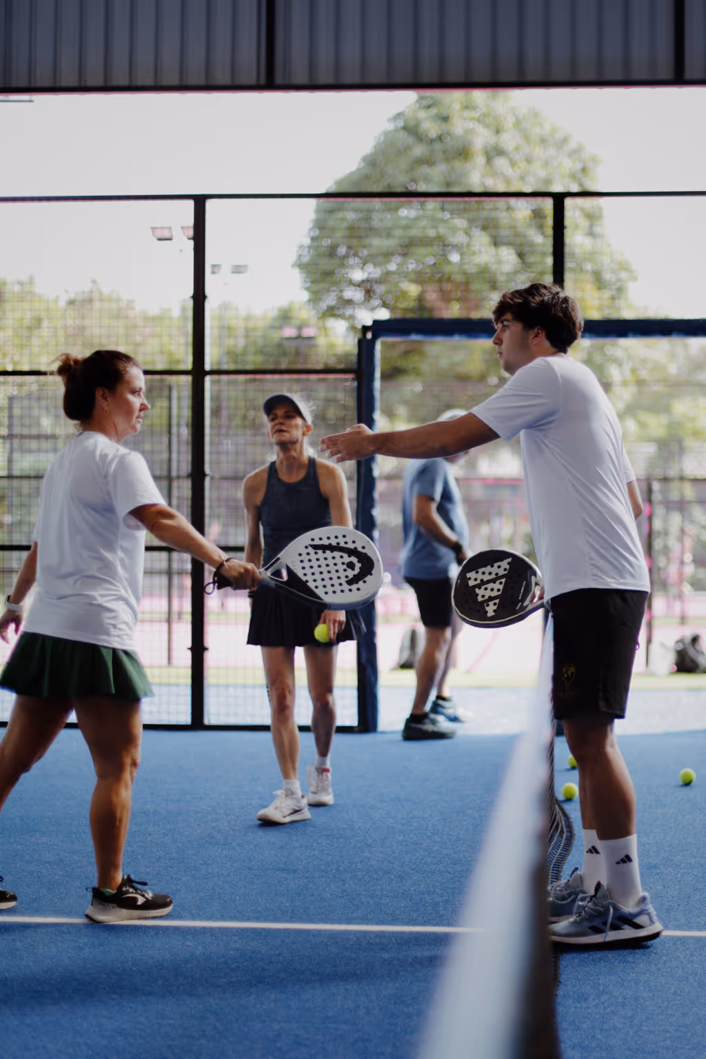 Padel coach in white Palaestra shirt teaching player on court in Koh Samui, Thailand