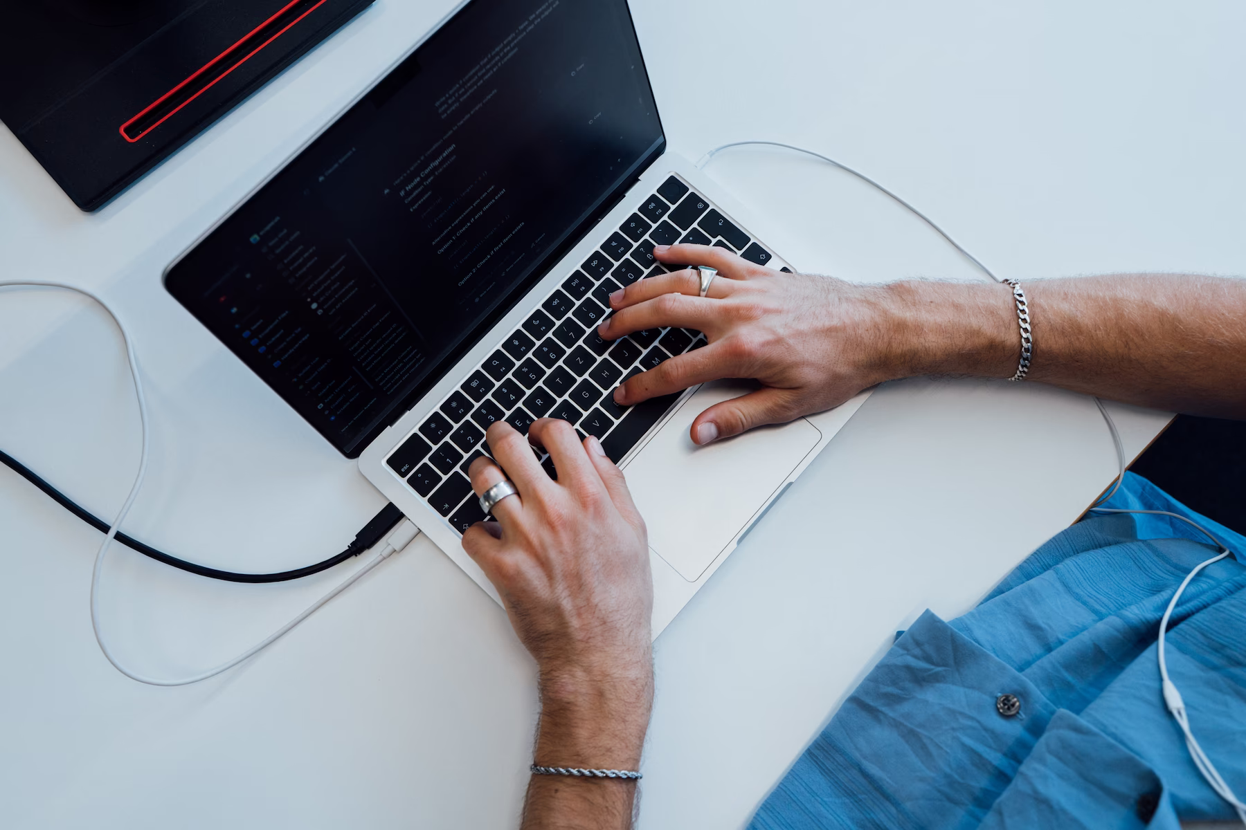 Laptop mit geöffneter Code-Ansicht und Hand auf Trackpad