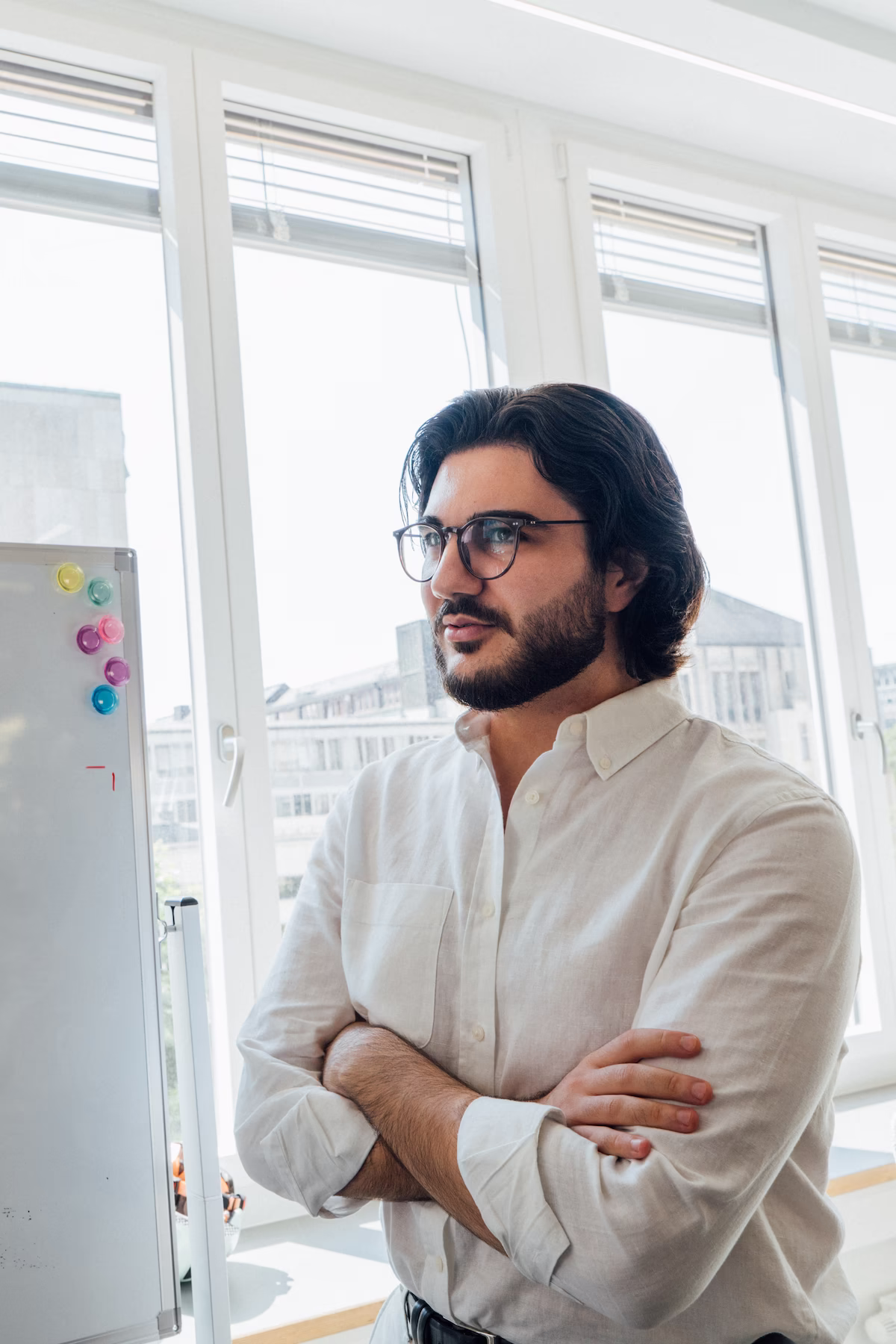 Mann mit Bart und Brille steht im Büro und blickt nach vorne