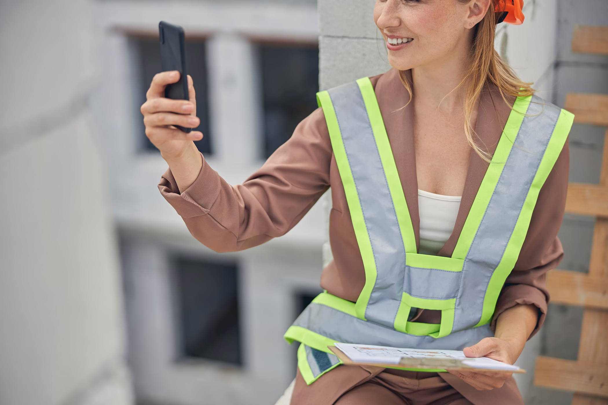 Mitarbeiterin mit Warnweste dokumentiert Daten per Smartphone