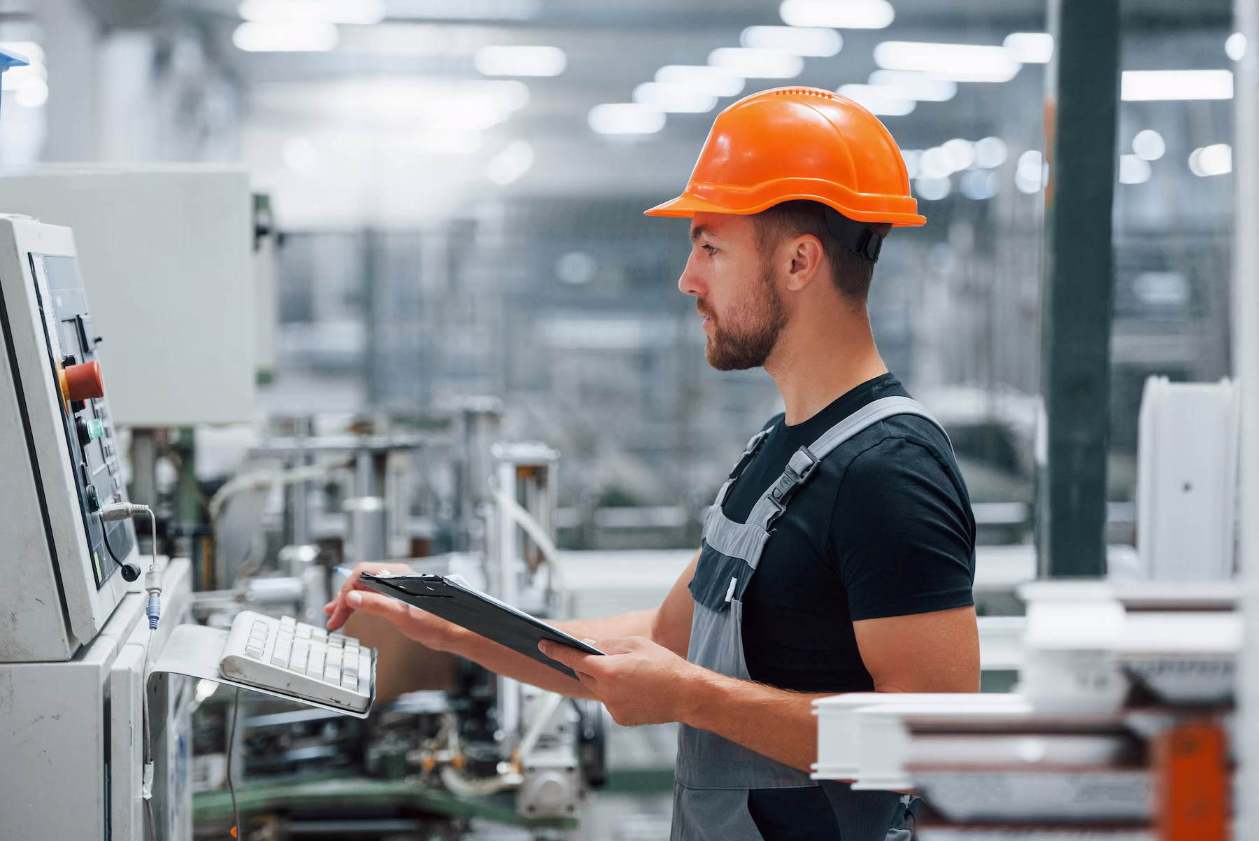 Arbeiter mit Helm überwacht Maschinen in der Produktion