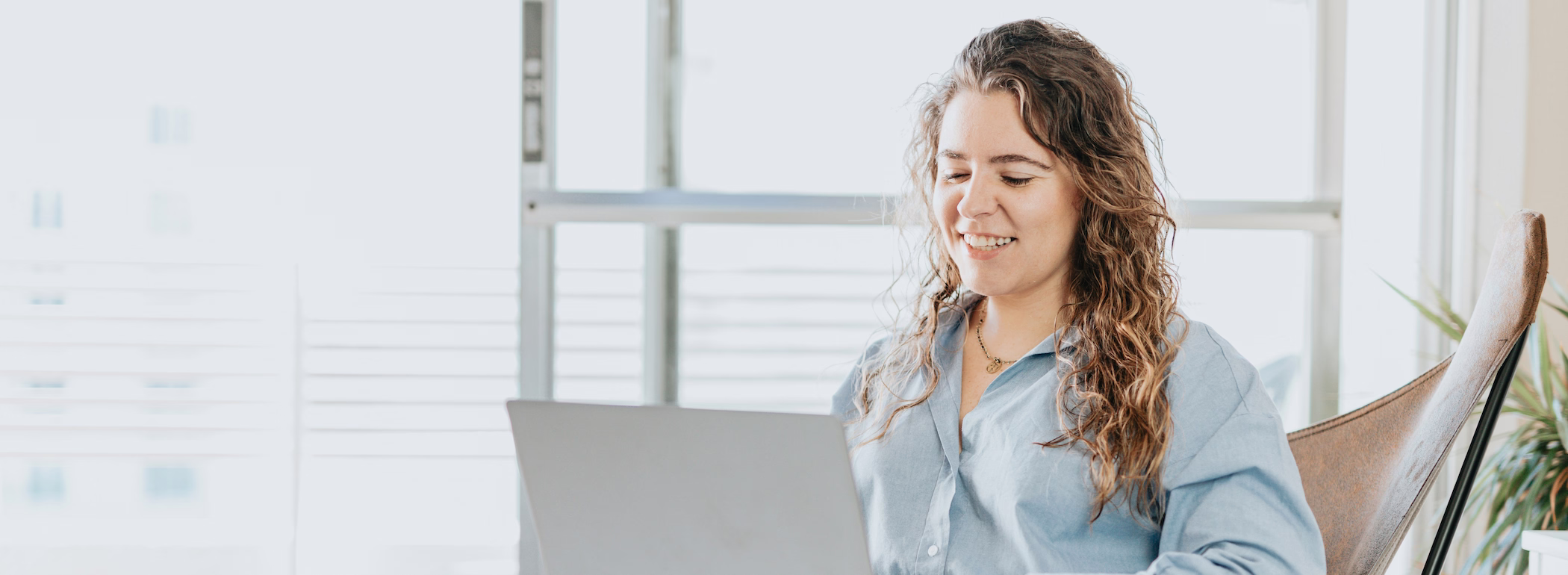 Mitarbeiterin arbeitet am Laptop am Fenster