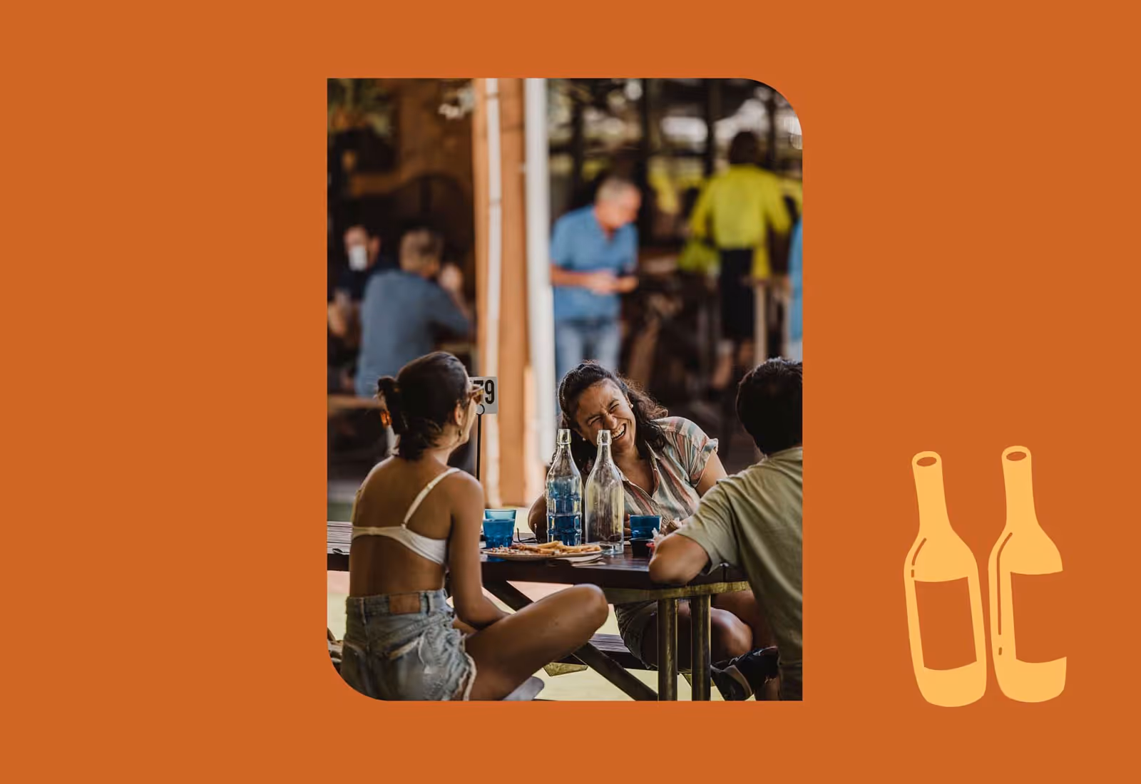 Friends enjoying drinks and conversation at an outdoor picnic table at The Henley Brook