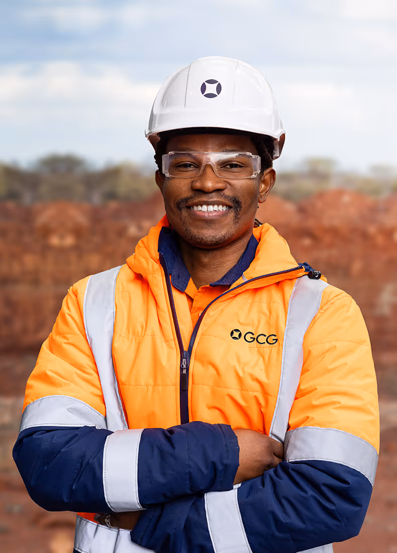 Male worker in GCG high-visibility jacket and helmet smiling with arms crossed