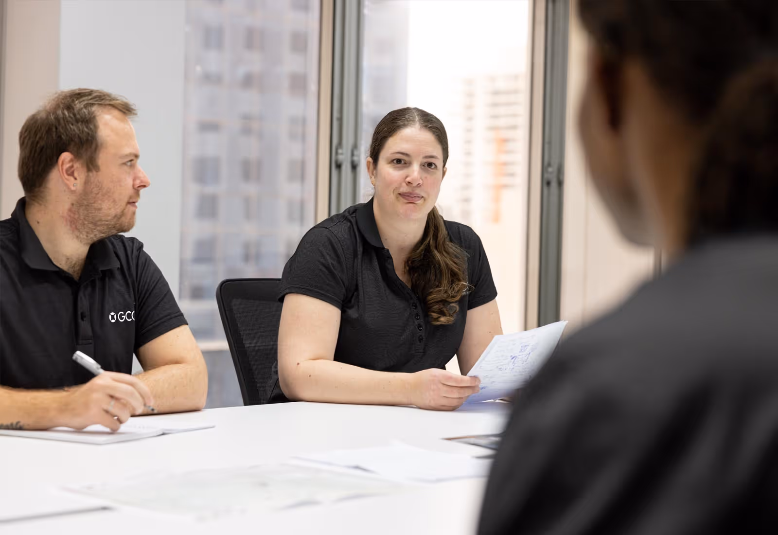 GCG office meeting with woman holding documents and man taking notes