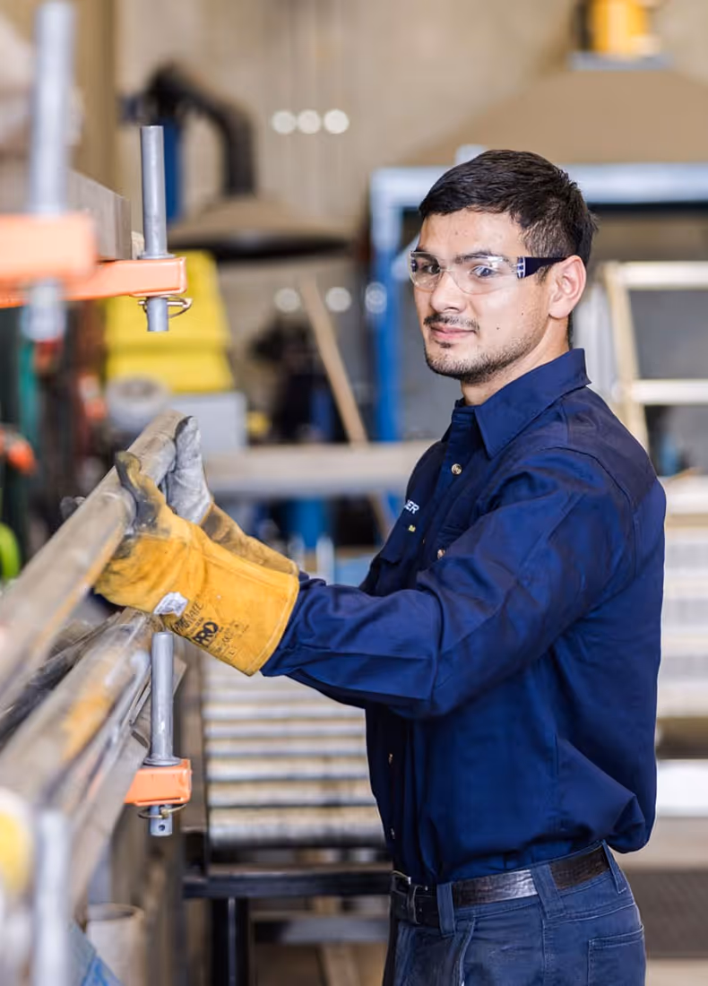 Welder wearing safety gloves and glasses operating equipment in workshop