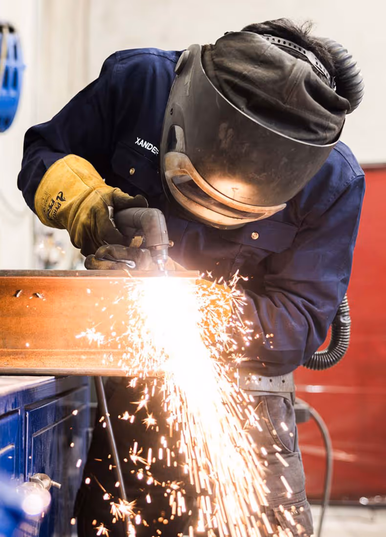 Welder named Xander using cutting torch with sparks flying in workshop