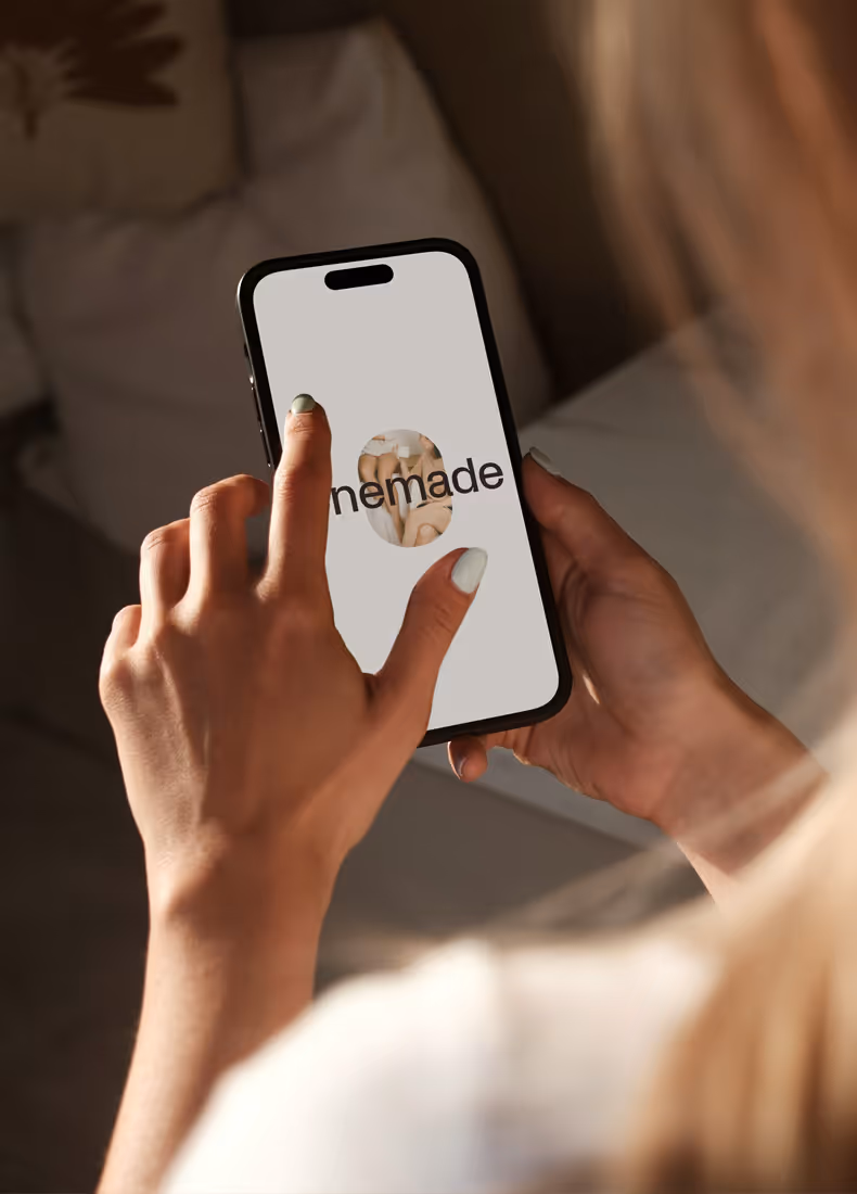 Person holding a smartphone displaying the Onemade logo on the screen.
