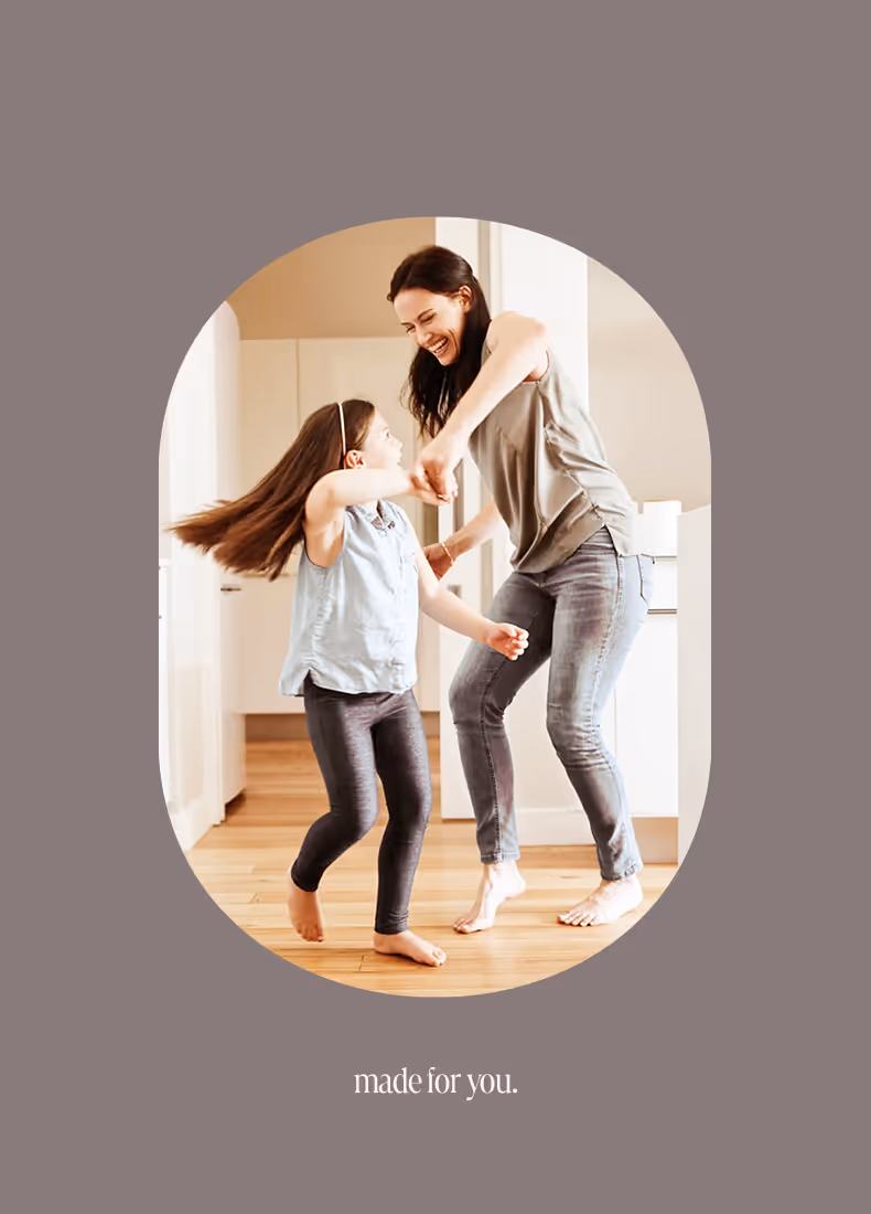 Mother and daughter dancing together in a bright kitchen with Made for you text.