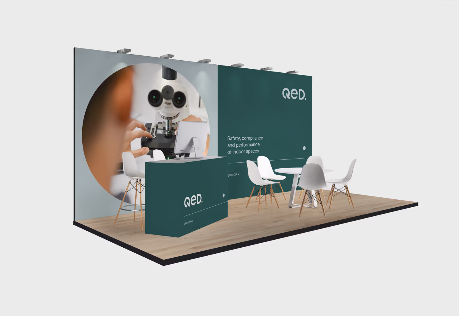 A QED exhibition booth setup featuring wall-to-wall brand messaging, large-scale imagery, and clean spatial layout with branded signage and seating.