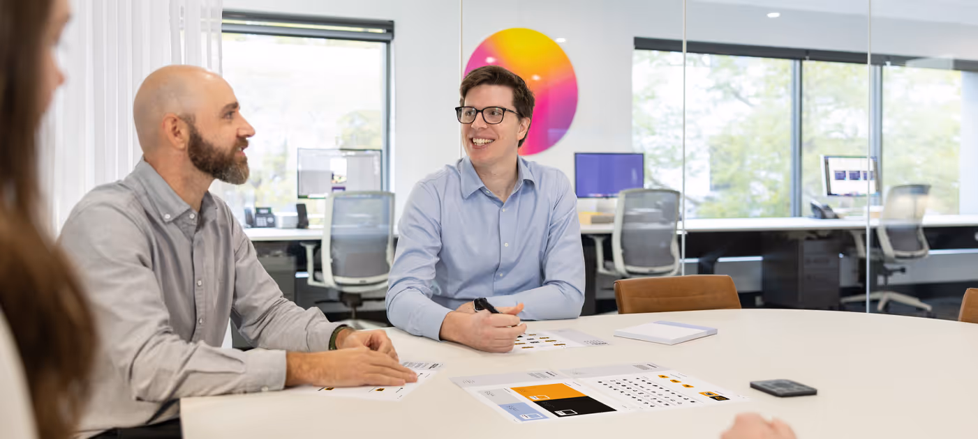 Branding strategy session in a modern studio environment, with team members collaborating over printed brand assets and colour systems, reflecting Four Stripes’ deep expertise in brand development and identity systems.