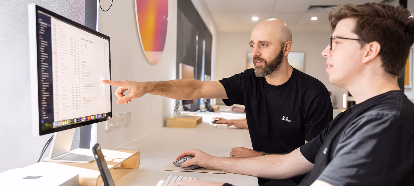 Creative team reviewing visual interface layouts on screen in a bright, minimalist workspace, highlighting Four Stripes’ design thinking and precision in crafting user-first digital experiences.