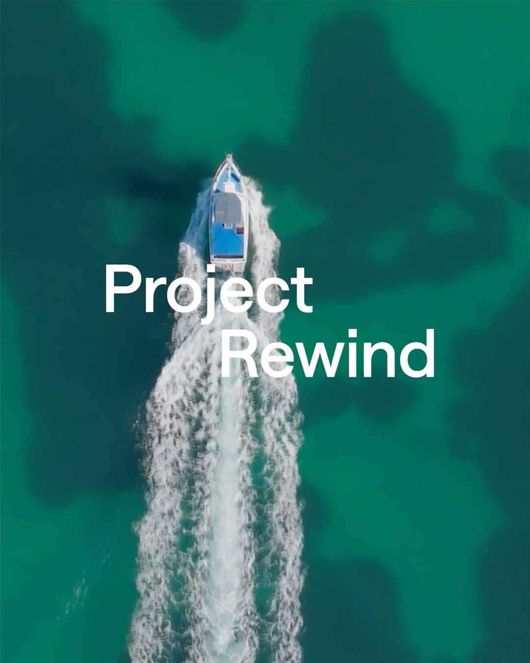 Aerial view of a white powerboat speeding through turquoise green ocean water, with Project Rewind text overlay.