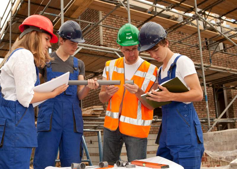 Des apprentis travaillant avec leur maître d'apprentissage sur un chantier pour la construction d'un bâtiment éco-conçu