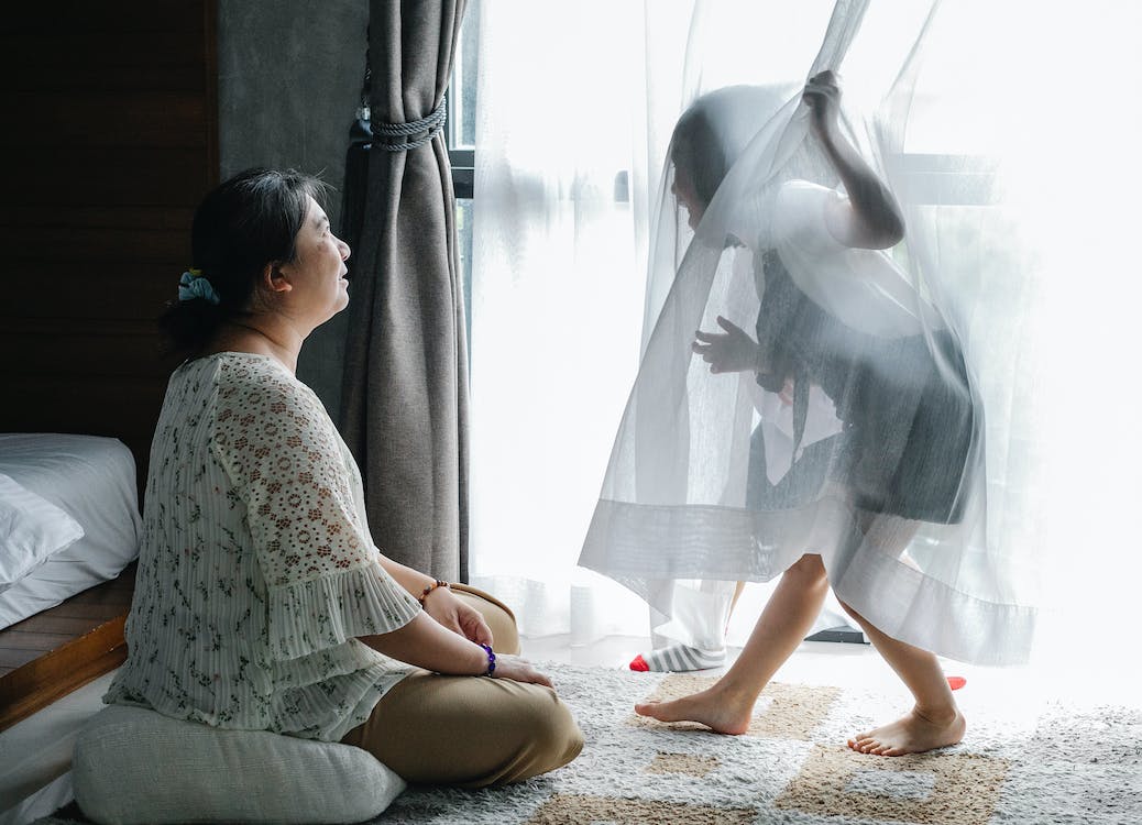 Free Anonymous little girl having fun with Asian grandmother sitting on floor in bedroom Stock Photo