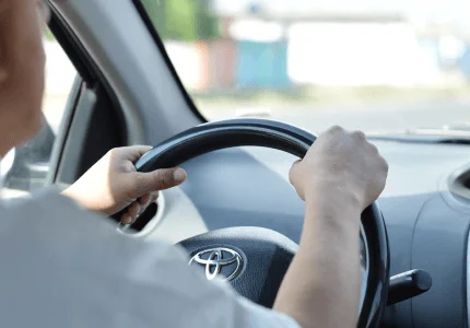 Person, die während der Fahrt ein Toyota-Lenkrad hält.