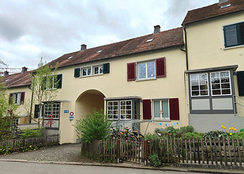 Gelbe Siedlung mit Mehrfamilienhäusern und einem Torbogen in der Mitte