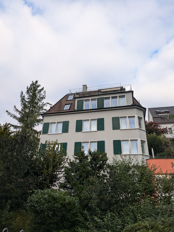 Graues Mehrfamilienhaus mit grünen Fensterläden