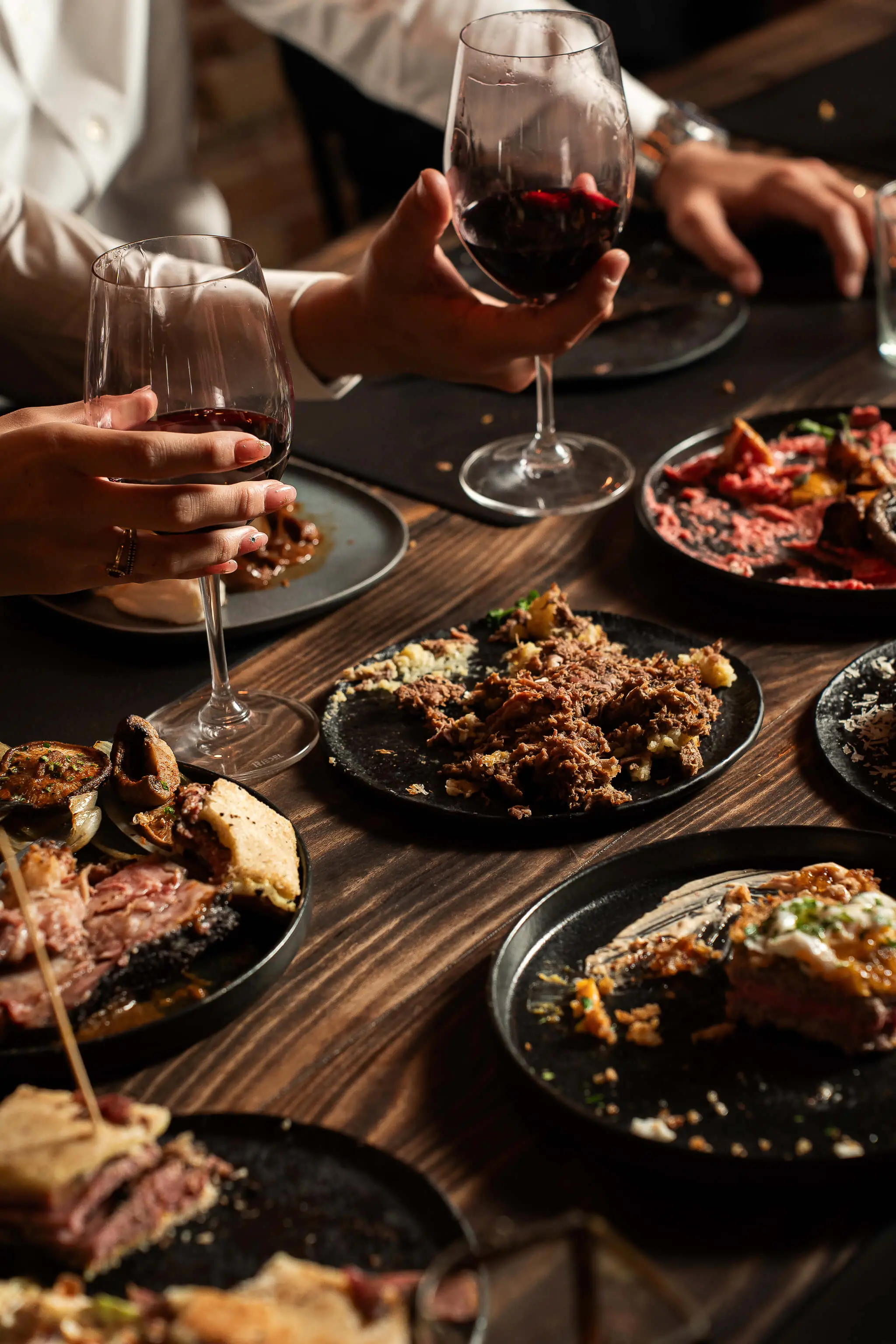 a table full of dishes to share with people drinking wine and connecting