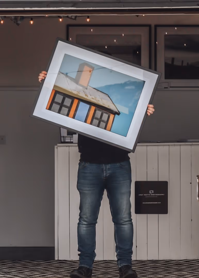 Andy Watts holding his photograph in his shop in folkestone 