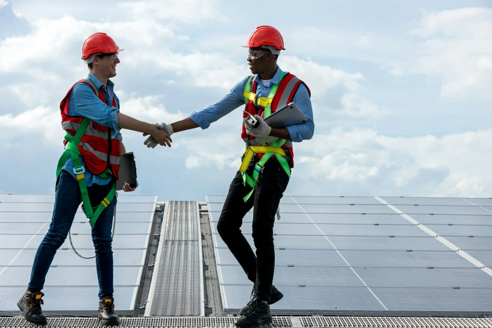 Zwei Bauarbeiter mit Helm stehen auf Solaranlage