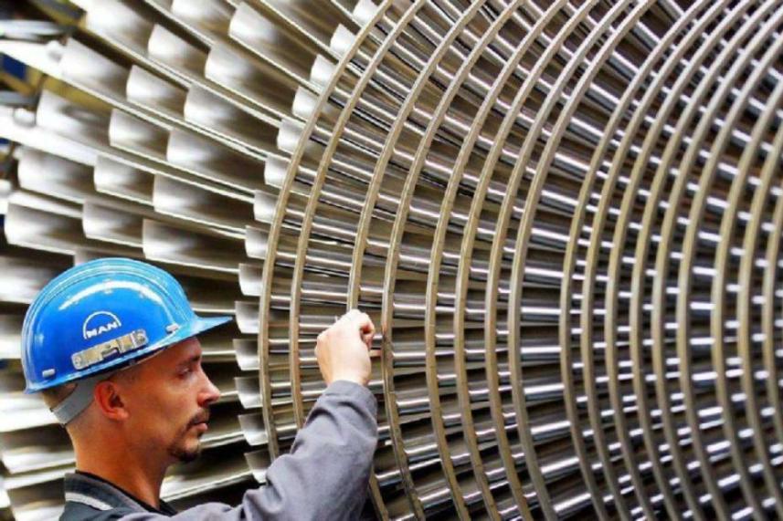 Arbeiter mit blauem Schutzhelm überprüft große Maschinenlamellen