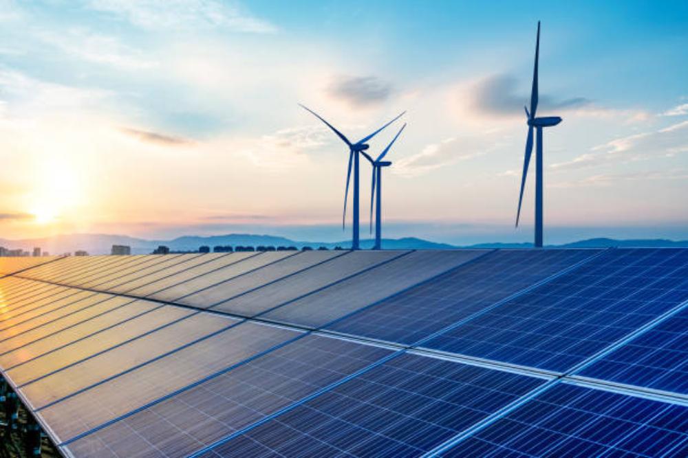 Solarpaneele mit Windrädern im Sonnenuntergang