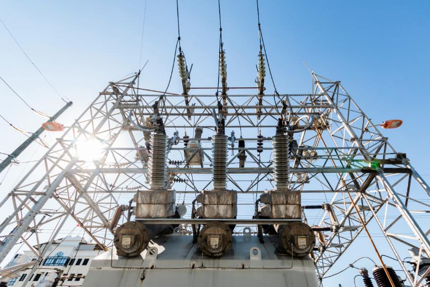 Strommast mit Sonne im Hintergrund
