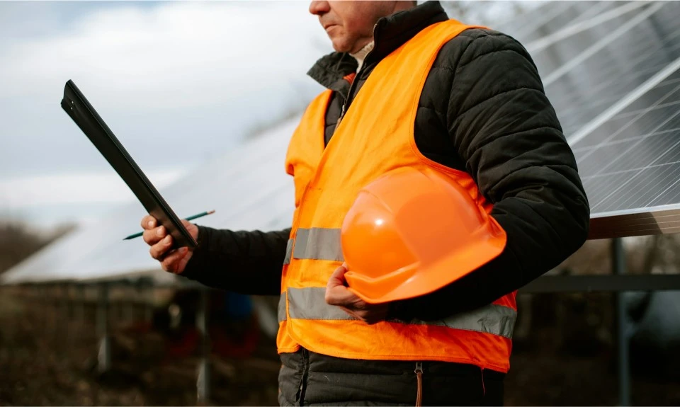 Bauarbeiter mit Helm und Tablet auf einer Solaranlage