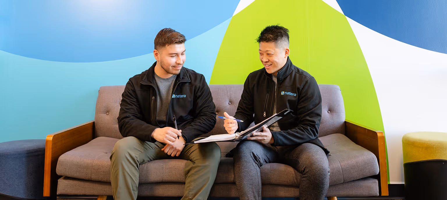 Two Natera employees reviewing lab tests in front of a Natera graphic wall.
