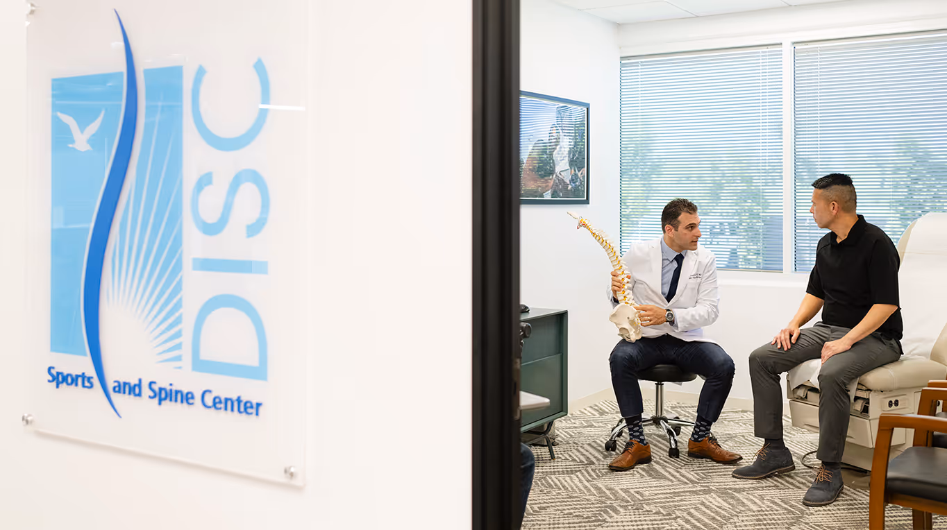 A doctor at DISC informs the patient on a spinal model.