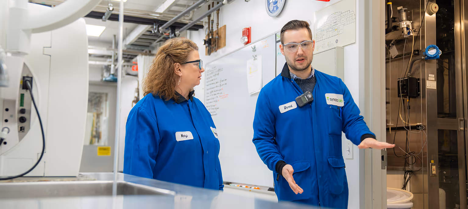 Synata employees, Mary and David walk through the biotech lab.