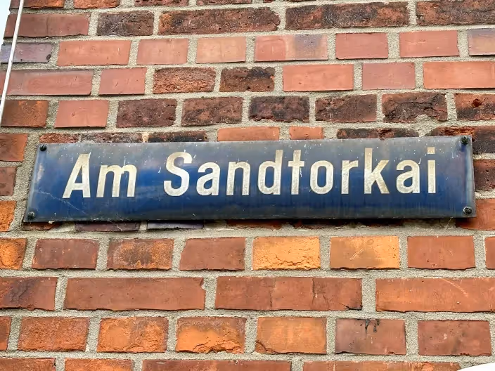 Straßenschild "Am Sandtorkai" an einer Backsteinmauer. 