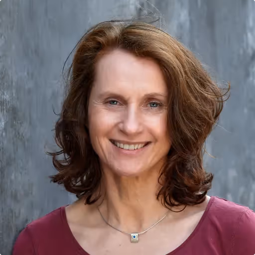 Frau lächelnd vor grauem Hintergrund. 