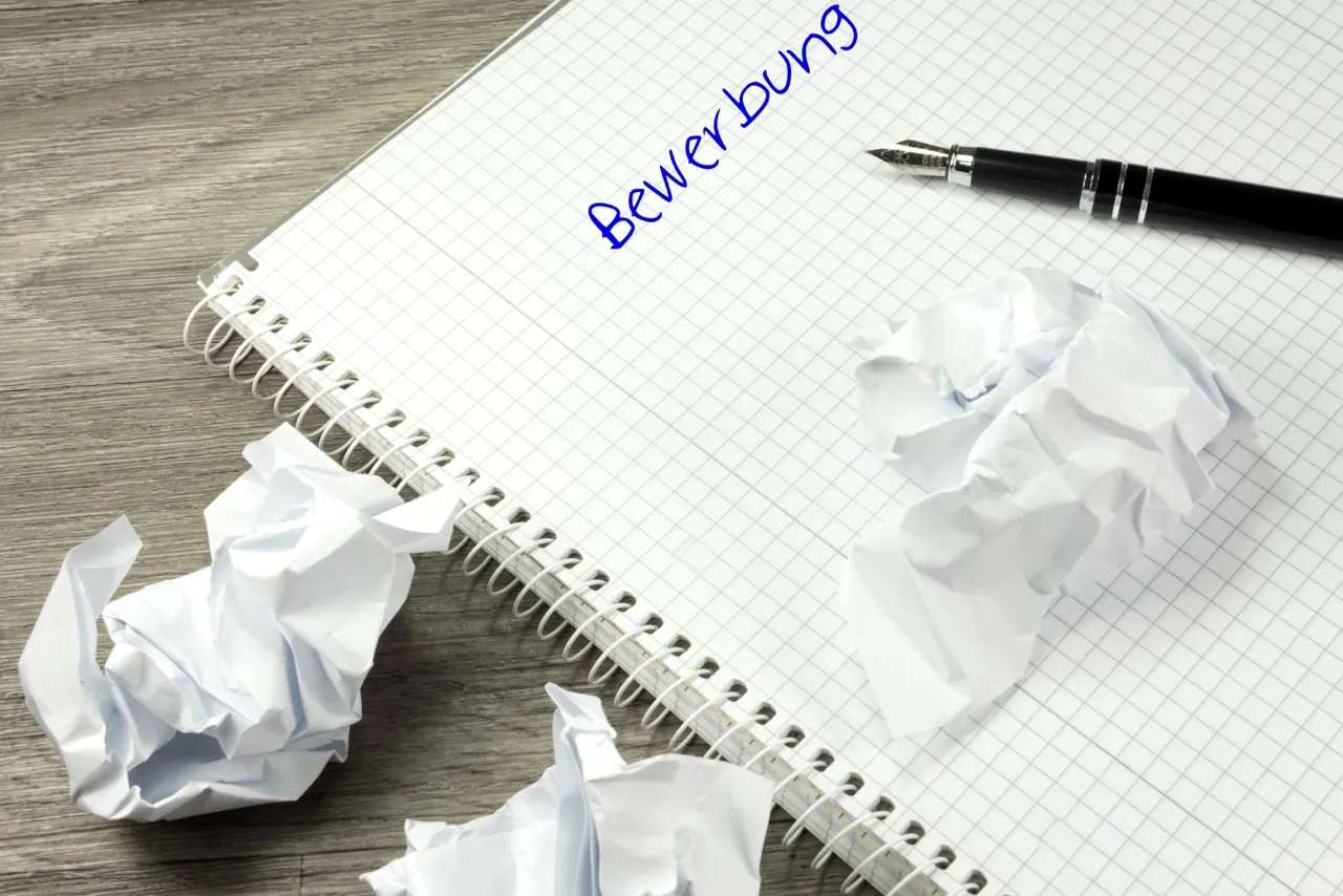 Notizbuch mit Stift und zerknülltem Papier.