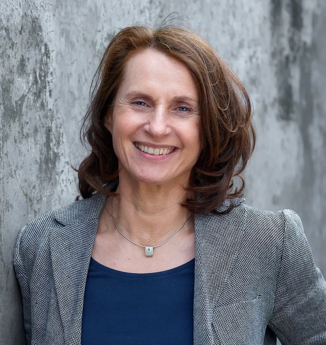Frau in einem grauen Blazer lächelnd. 