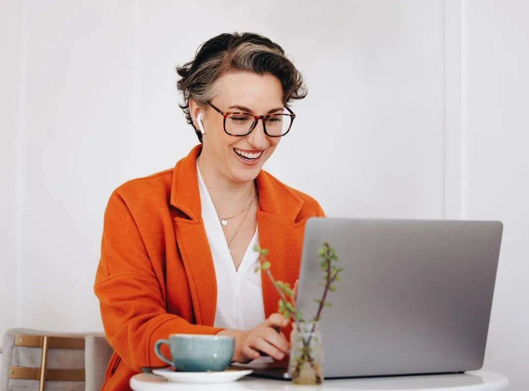 Frau in einem hellen Büro mit Tasse, lächelnd.