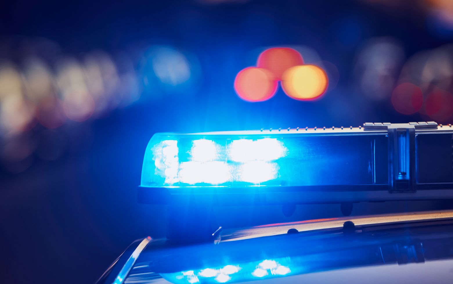 Close-up of a blue police car emergency light flashing at night with blurred background lights.