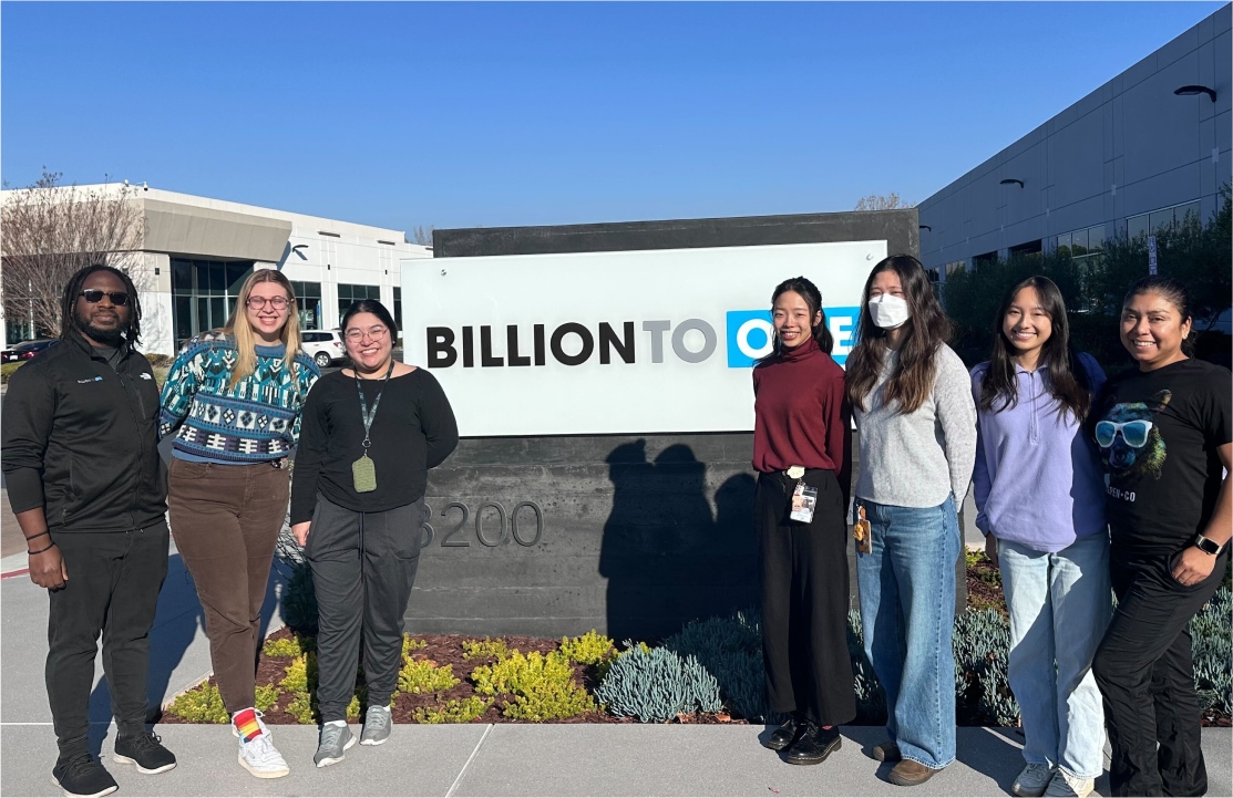 A group of people in front of the BillionToOne sign