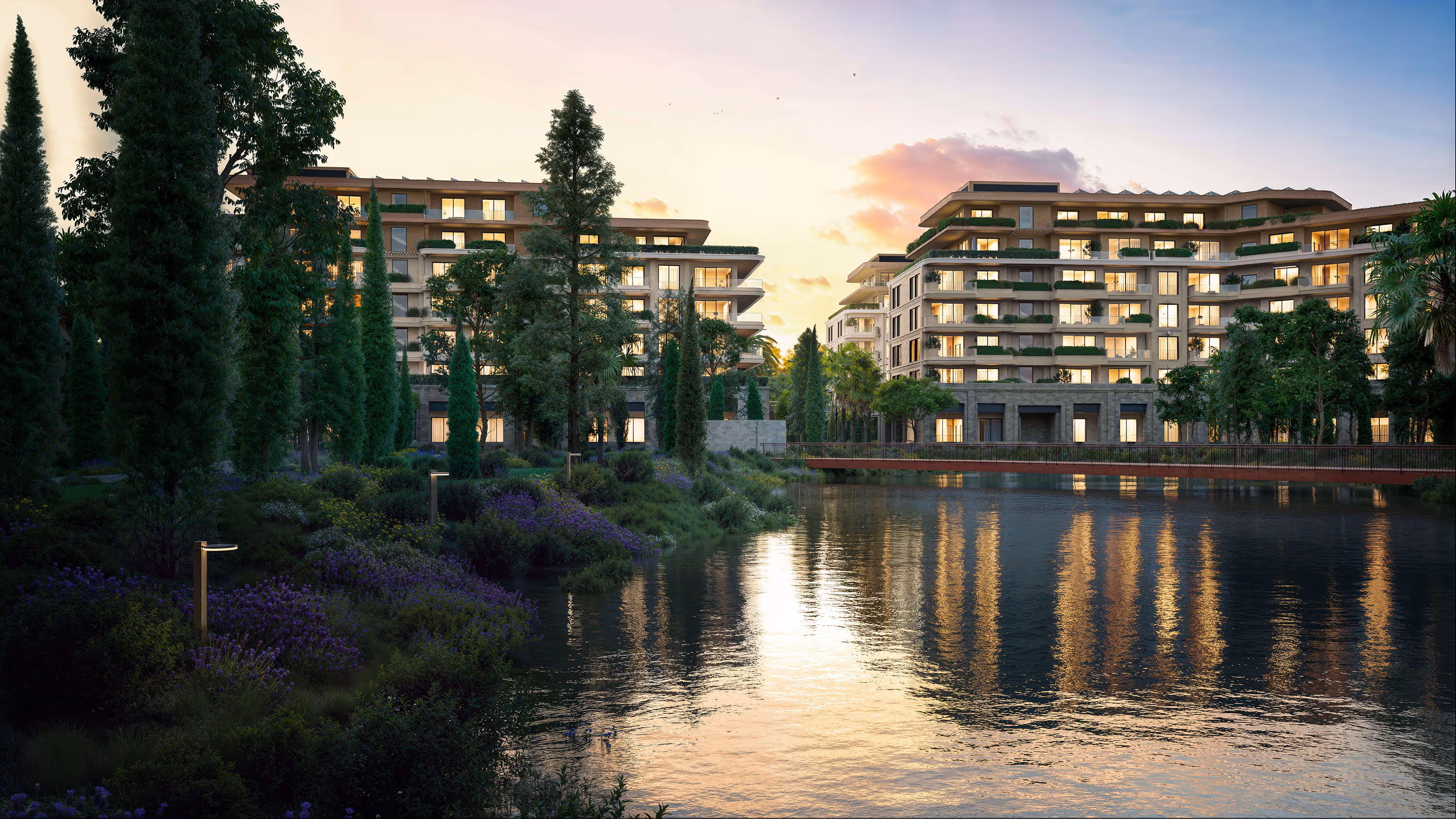 Evening view of Porta Rai residences reflected in a landscaped lake with illuminated windows.