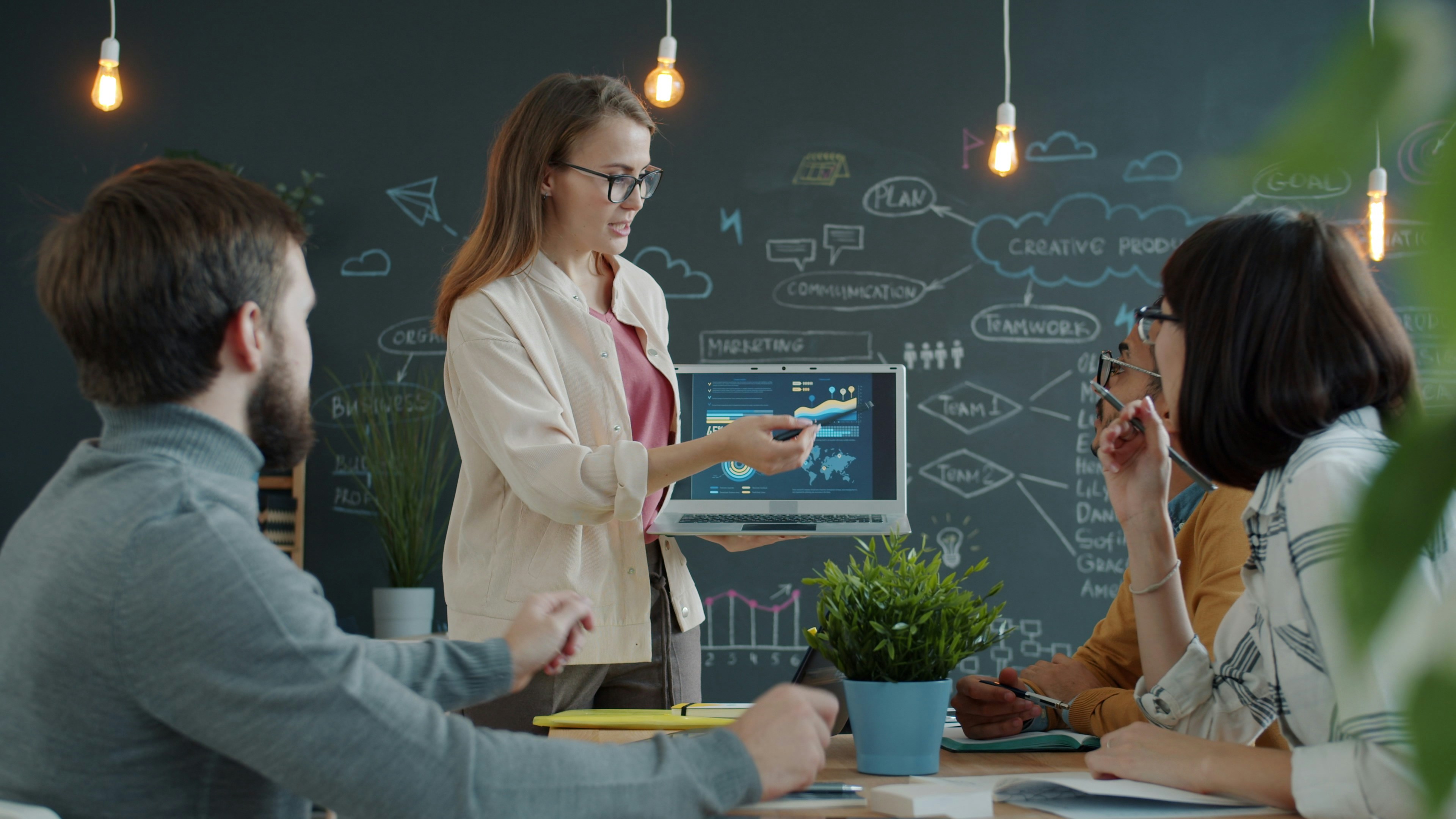 Frau hält Präsentation vor Kollegen über die Einführung von KI in Unternehmen