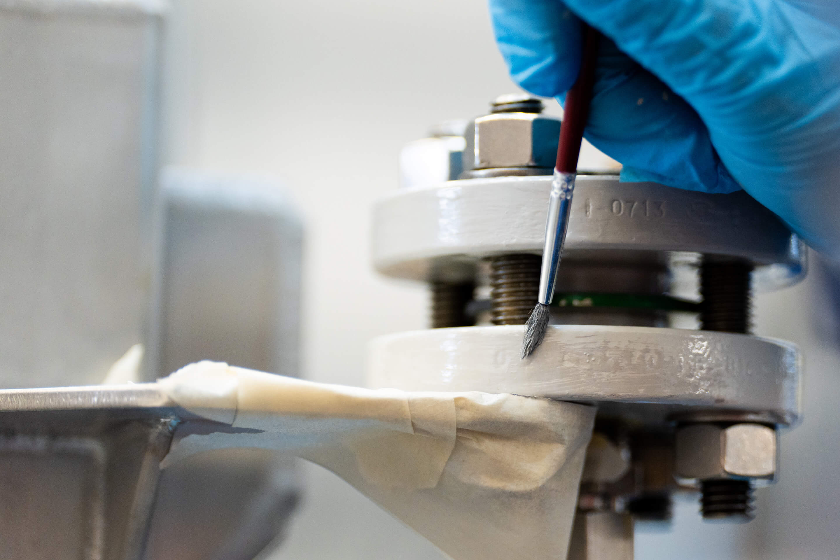 A close up shot of a piece of equipment being painted white with a fine brush
