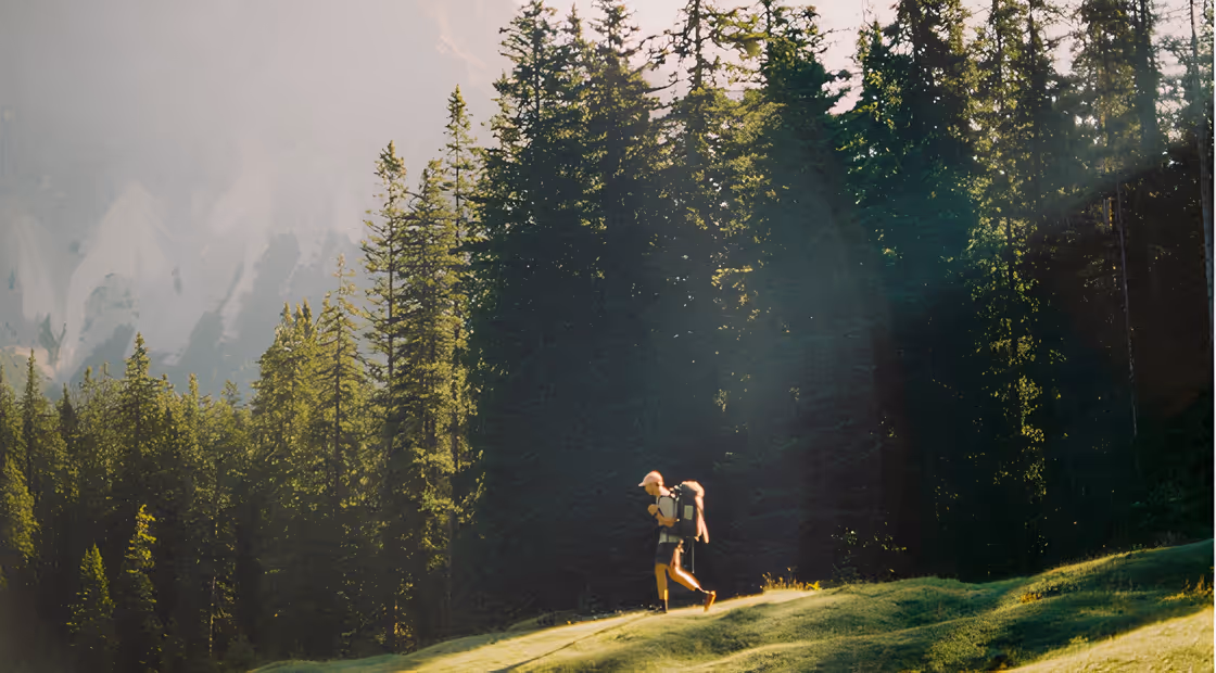 Trekkeur marchant en forêt au soleil, illustration de l’article blog sur la respiration en trek.