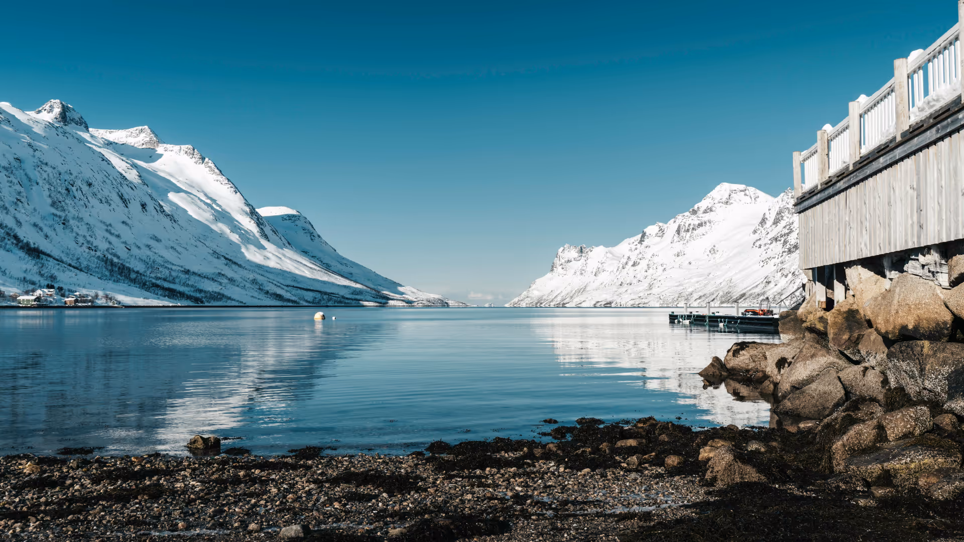 Paysage norvégien au crépuscule : fjord calme entouré de montagnes abruptes, lumière douce, atmosphère silencieuse et contemplative.