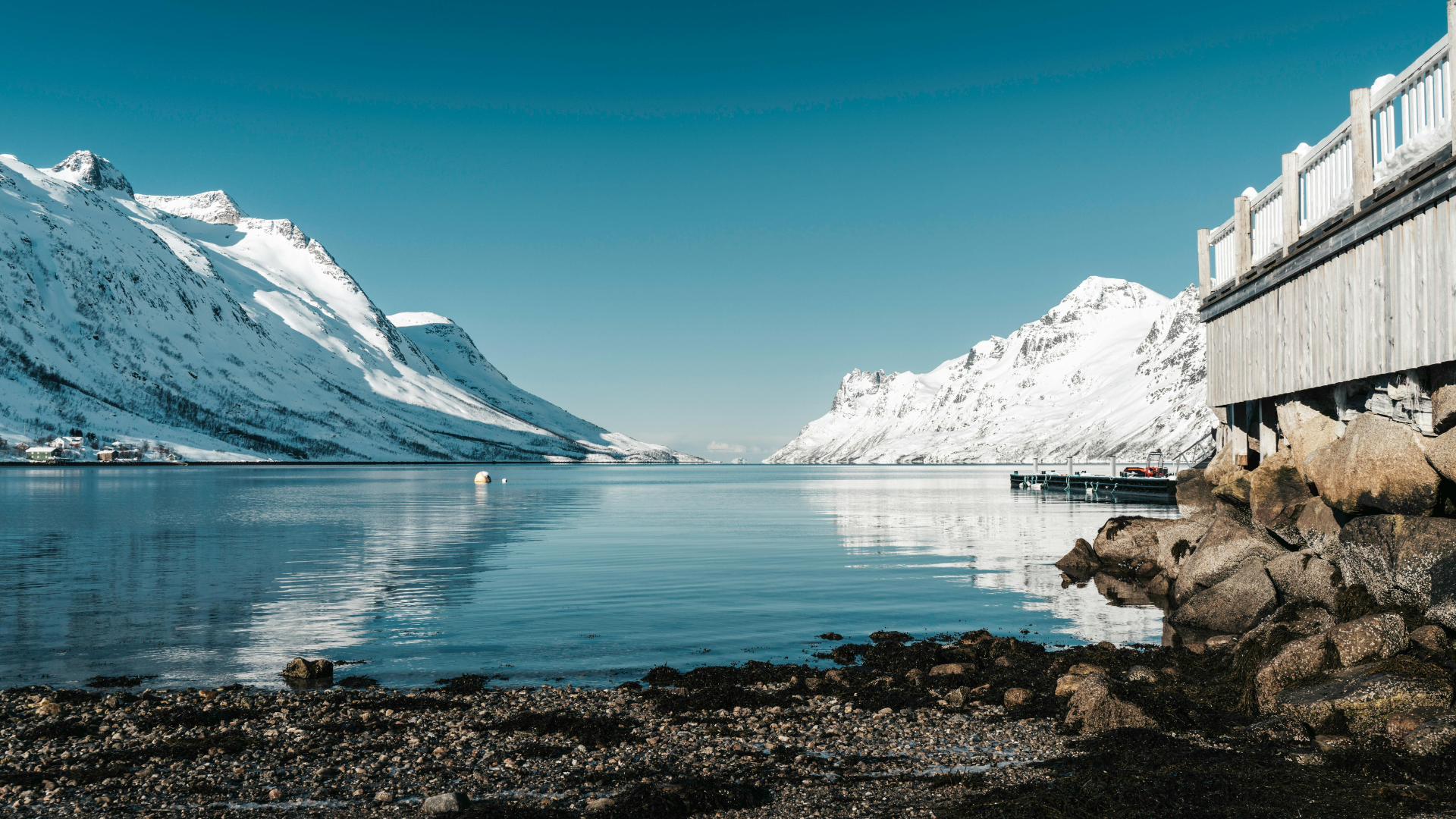 Paysage norvégien au crépuscule : fjord calme entouré de montagnes abruptes, lumière douce, atmosphère silencieuse et contemplative.