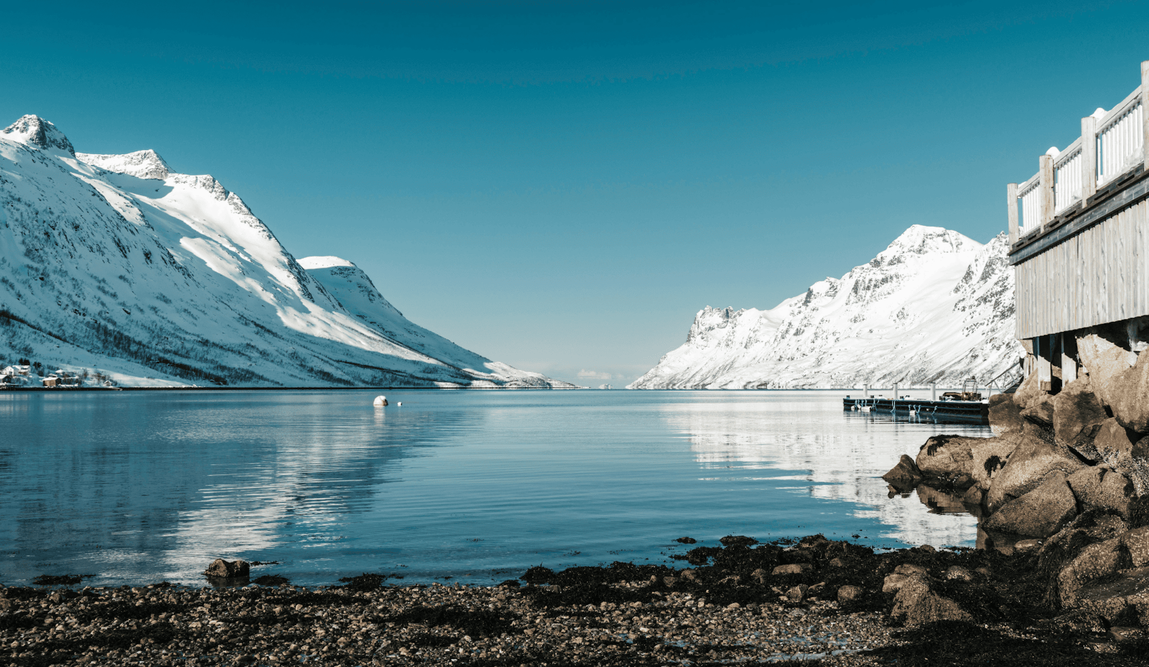 Paysage norvégien au crépuscule : fjord calme entouré de montagnes abruptes, lumière douce, atmosphère silencieuse et contemplative.